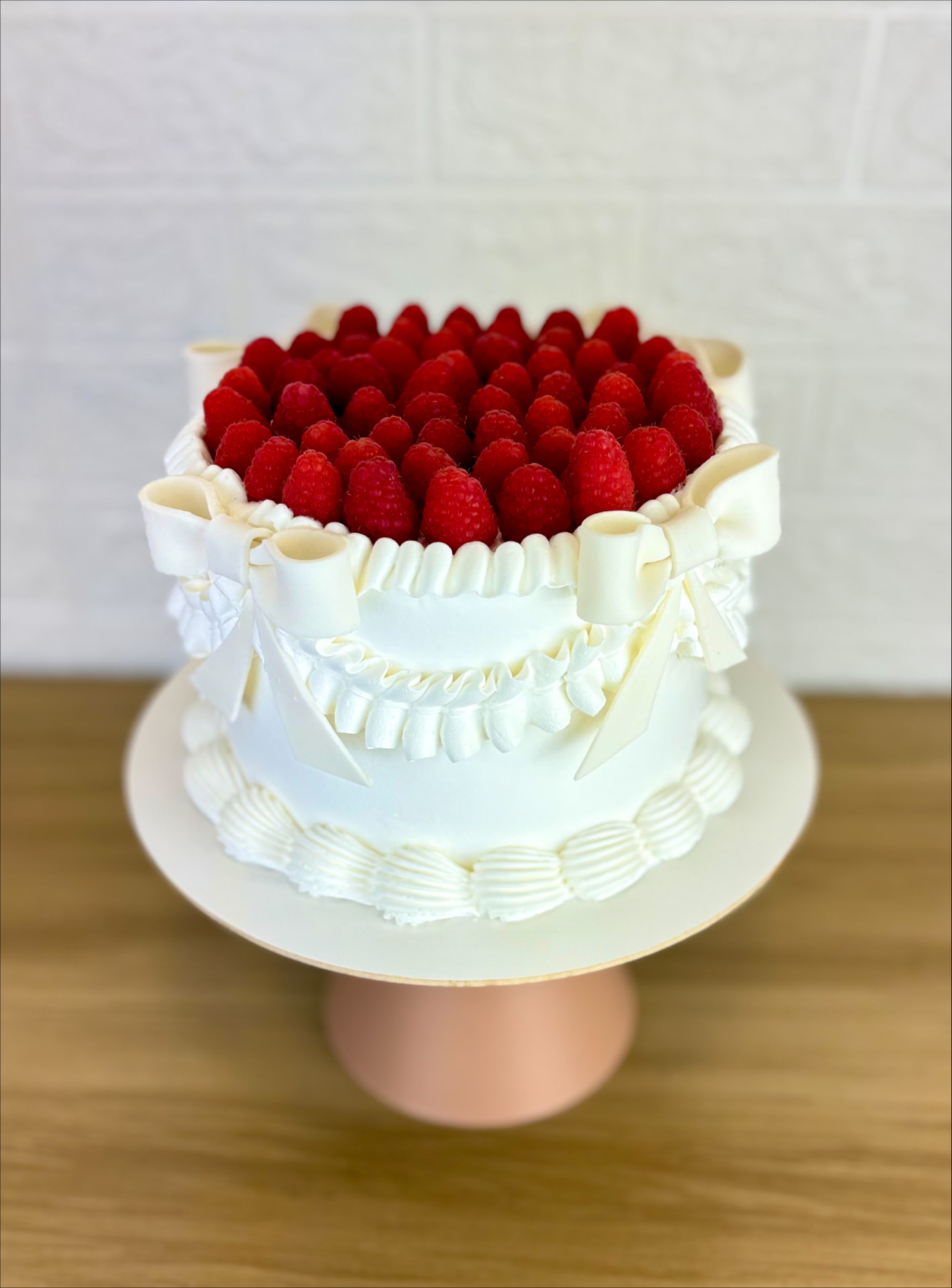 Bolo branco decorado com laços e framboesas